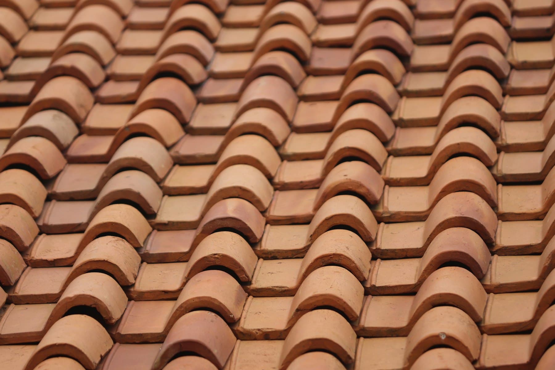 Hand-laid Spanish clay barrel and pan tiles on a warm terracotta roof, close macro